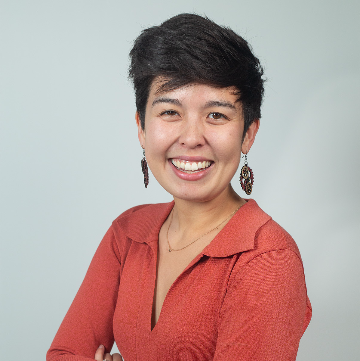 A photo of Leslie Niiro in front of a gray background.