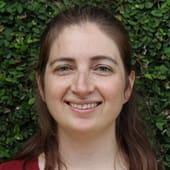 A headshot of Rachael Harding against a green leafy background.