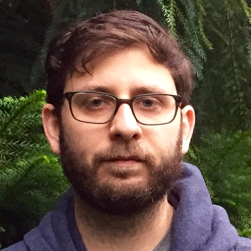 A headshot of David Taylor against a green, leafy background.