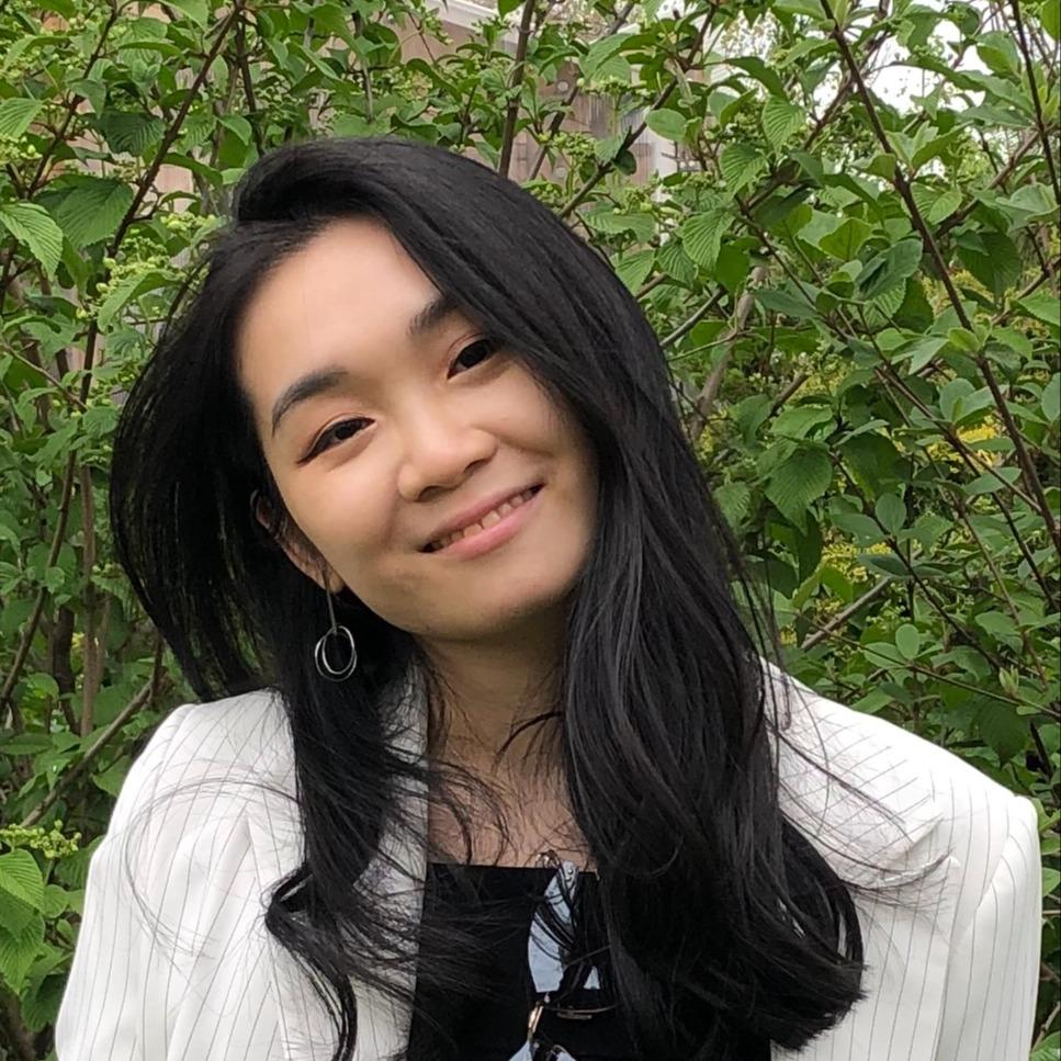A photo of Rebecca Weng in front of greenery.
